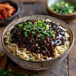 ajangmyeon - Thick noodles coated in a rich black bean sauce with pork, vegetables and garnished with cucumber and sesame seeds.